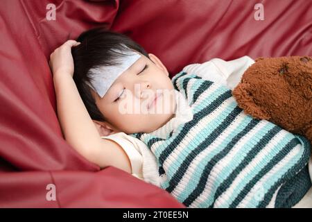 Sie war krank und hatte einen fiebersenkenden Fleck auf der Stirn. Sie lag auf dem Bett. Stockfoto