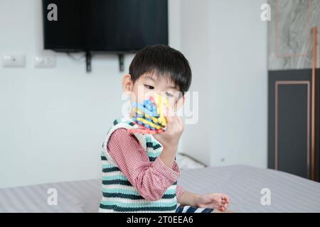 Asiatischer Junge, der freudig mit Puzzles auf dem Bett spielt Stockfoto