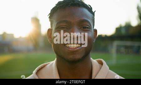 Männlicher Athlet Porträt fröhlich lächelnder ethnischer junger Sportler Afroamerikaner Mann athletischer Fit Guy Fußballer Läufer draußen am Morgen Sonnenaufgang Stockfoto