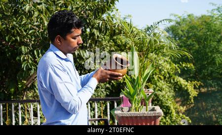 Hinduistische Gläubige, die dem Sonnengott zu Hause auf der Terrasse Wasser oder Ardhya anbieten. Stockfoto