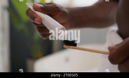Close-up-Hände weiße Zahnpasta aus der Tube auf Zahnbürste herausdrücken Zahnpflege Morgendprozedur Mundhygiene verhindern Zahnkaries unbekannt afrikanisch Stockfoto