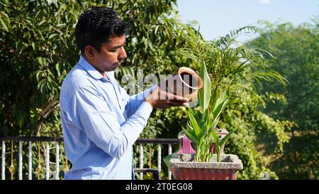 Hinduistische Gläubige, die dem Sonnengott zu Hause auf der Terrasse Wasser oder Ardhya anbieten. Stockfoto