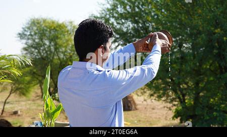 Hinduistische Gläubige, die dem Sonnengott zu Hause auf der Terrasse Wasser oder Ardhya anbieten. Stockfoto