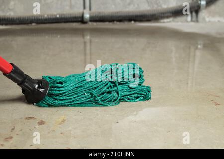 Reinigung von Hochwasser im Elektroraum oder Untergeschoss Tiefes Wasser auf dem Boden. Nahaufnahme des Wischs in Wasser mit unscharfem, großem Elektrokabel. Wasserschaden fr Stockfoto