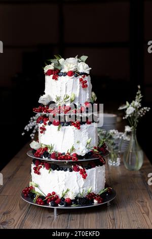 Dreistöckige Hochzeitstorte mit Beeren, Früchten und weißen Blumen Stockfoto