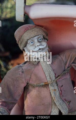 Eine heruntergekommene Weihnachtsmann-Figur auf einem Sitz im Freien Stockfoto