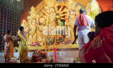 Howrah, West Bengal, Indien - 5. Oktober 2022: Göttliche Shahkh Naad, hinduistische Devotee Frau bläst Muschelschale, während Purohits Göttin Durga verehren. Stockfoto