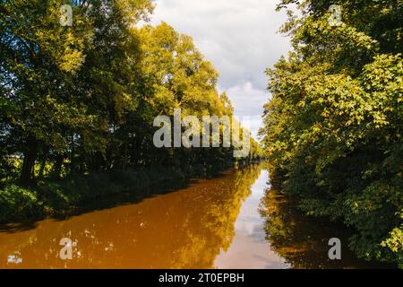 Entwässerungsgraben im Huntemarsch, gefüllt mit hellbraunem Moorwasser nach Uferreinigungsmaßnahmen. Stockfoto