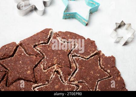 Ausgerollter Schokoladen-Keksenteig auf Pergamentpapier. Glutenfreies Mandelmehl Schokoladenkeks. Hintergrund zum Backen von Weihnachtskeksen. Schweizer Rezept „Basler B Stockfoto