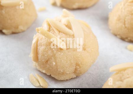 Glutenfreier Mandelmehl-Keks, fertig zum Backen. Nahaufnahme von ungebackenem rohen Keksenteig. Gruppe von runden Keksenteigbällchen mit Mandelscheiben auf Parch Stockfoto