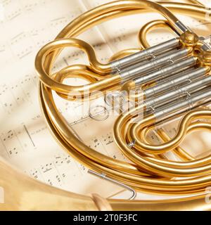 Nahaufnahme eines Horns auf Notizblättern. Ein Messinginstrument aus glänzend goldenen Röhren, das von Spielern in professionellen Orchestern oder verwendet wird Stockfoto