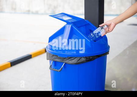 Nahaufnahme der Frau, die leere Plastikwasserflasche in den Recyclingbehälter wirft Stockfoto