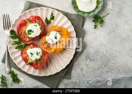 Gefüllte rote und gelbe Paprika mit Couscous, braunem Reis und mit griechischer Sauce und Olivenöl auf rustikalem hölzernem Hintergrund braten. Gesunde di Stockfoto