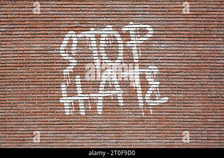 Phrase Stop Hass Spray in weiß auf eine Ziegelwand gemalt Stockfoto