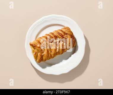 Frisch gebackenes süßes Brötchen auf weißem Teller, Blick von oben Stockfoto