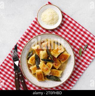 Italienische hausgemachte Gnocchi mit Kartoffeln, Käse und Salbeibutter, serviert auf Teller auf roter Serviette Stockfoto