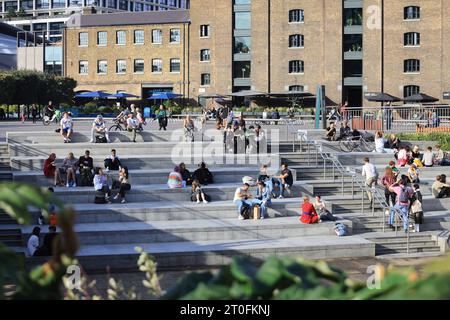 Ungewöhnlich warmes Wetter in London, hier am Granary Square, wo die Menschen sich in der Sonne entspannen, im Kings Cross im Norden Londons, Großbritannien Stockfoto