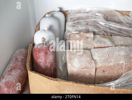 Gefrorene Fleischverpackungen im Gefrierschrank. Viele Würstchen und Blöcke. Rohkost oder BARF für Hunde, Katzen und Haustiere. Hackiges Hühnchen und Rindfleisch aus biologischem Anbau Stockfoto