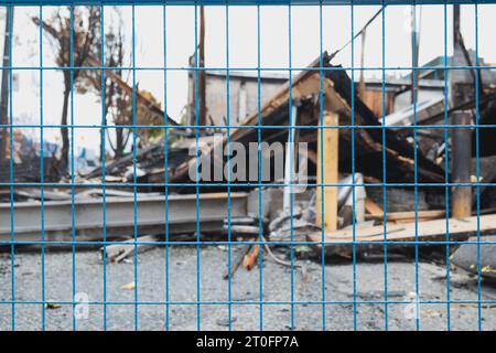 Abstrakt verbranntes Gebäude hinter Bauzaun. Nach einem Brand durch eine defokussierte Gebäudestruktur eingezäunt. Totalverlust der Struktur durch einen Brand. Verkohltes Colla Stockfoto
