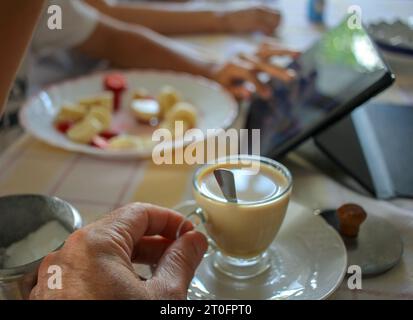 Einen Kaffee mit Milch trinken in Begleitung meines Sohnes, der die Tafel beobachtet Stockfoto