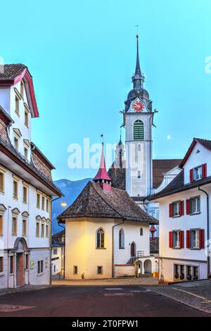 Nachtszene in Schwyz, Schweiz mit der St. Pfarrkirche Martin mit imposantem Turm und St. Michael Chapel steht oben auf dem Kerchel, A Stockfoto