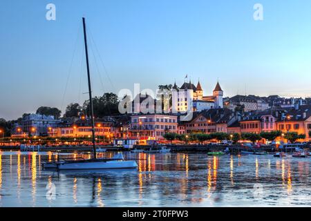 Sonnenuntergang in Nyon, Waadt, am Ufer des Leman-Sees (Genfersee), Schweiz, mit dem mittelalterlichen weißen Schloss mit Blick auf die Szene. Stockfoto