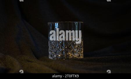 Ein einsames Glas Whiskey, vor einem eleganten grau-schwarzen Hintergrund, verkörpert Raffinesse und die Essenz des kontemplativen Stockfoto