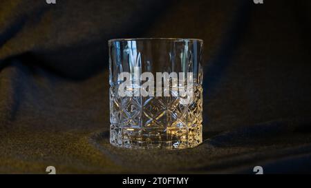 Ein einsames Glas Whiskey, vor einem eleganten grau-schwarzen Hintergrund, verkörpert Raffinesse und die Essenz des kontemplativen Stockfoto