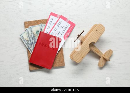 Flache Lay-Komposition mit Reisepass, Tickets und Flugzeugmodell auf weißem Holztisch. Geschäftsreise Stockfoto