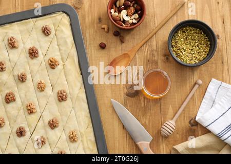 Ich mache köstliche Baklava. Backpfanne mit Teig und Zutaten auf Holztisch, flach liegend Stockfoto