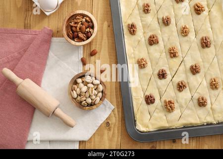 Ich mache köstliche Baklava. Backpfanne mit Teig und Zutaten auf Holztisch, flach liegend Stockfoto