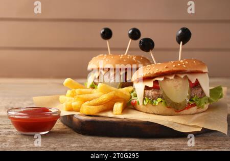 Süße Monster Burger serviert mit Pommes frites und Ketchup auf Holztisch. Halloween Party Essen Stockfoto