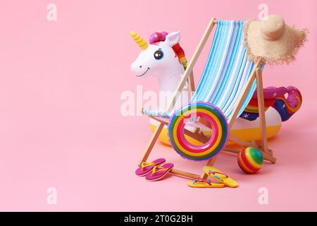 Liegestuhl, Flipflops und andere Strandaccessoires auf rosafarbenem Hintergrund, Platz für Text. Sommerurlaub Stockfoto