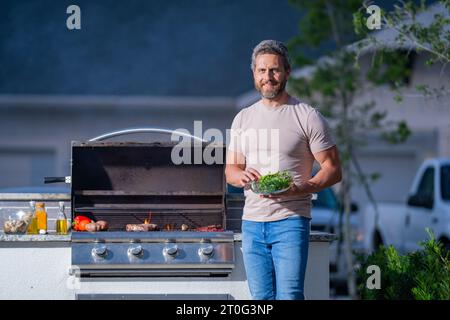 Männer, die auf dem Grill im Hof kochen. Kochen Sie auf einem Grillgrill und bereiten Sie Fleisch zu Stockfoto