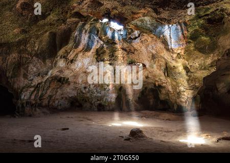 Quadiriki-Höhle im Arikok-Nationalpark, Aruba. Sonnenstrahlen reichen von den Öffnungen im Höhlendach bis zum Boden. Stockfoto