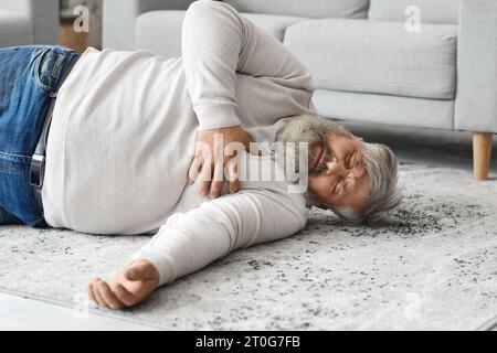 Bewusstloser älterer Mann, der zu Hause auf dem Boden liegt. Das Konzept des Herzinfarktes Stockfoto