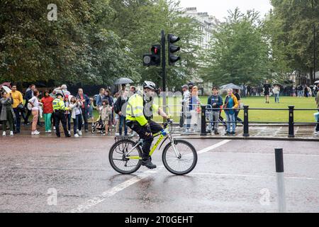 Londoner Polizist, der während des Wachwechsels im Buckingham Palace Polizeifahrräder fährt, als Teil der Menschenmassen-Kontrolle, London, England, Großbritannien Stockfoto