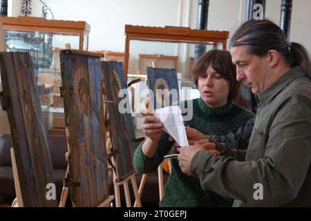 Kiew, Ukraine. Oktober 2023. Die ukrainischen Künstler Sonja Atlantowa und Oleksander Klymenko stehen vor ihren Gemälden während der Präsentation ihrer Werke im Museum für Angewandte Kunst. Das Paar malt traditionelle orthodoxe Ikonen auf Brettern alter Munitionskisten, die im ukrainischen Verteidigungskampf gegen Russland verwendet wurden. Quelle: Friedemann Kohler/dpa/Alamy Live News Stockfoto