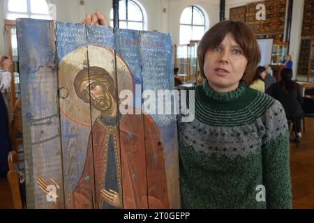 Kiew, Ukraine. Oktober 2023. Die ukrainische Künstlerin Sonja Atlantowa steht neben einer modernen Ikone im Museum für angewandte Kunst in Kiew. Das Künstlerpaar Atlantowa/Klymenko malt traditionelle orthodoxe Bilder von Heiligen auf Brettern alter Munitionskisten, die im ukrainischen Verteidigungskampf gegen Russland verwendet wurden. Quelle: Friedemann Kohler/dpa/Alamy Live News Stockfoto