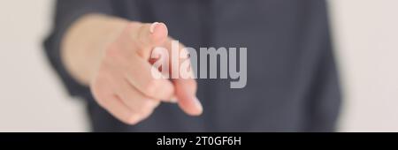 Die verschwommene Frau zeigt auf Beige mit dem Zeigefinger auf die Kamera Stockfoto