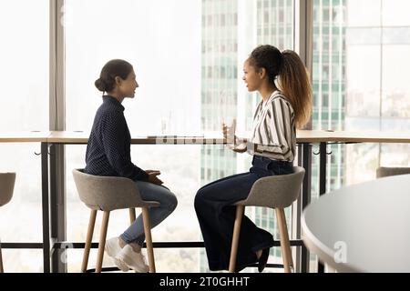 Positive Bürofreunde, Frauen, die im großen Stadtfenster des Büros sprechen Stockfoto