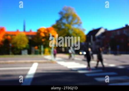 Unscharfes, unscharfes Foto von Menschen, die die Straße auf Zebras überqueren, und gelben Herbstbäumen außer Fokus, Bokeh Hintergrund Stockfoto