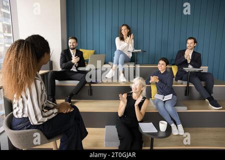 Verschiedene Gruppen applaudieren junge afroamerikanische Moderatorin Stockfoto
