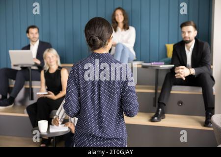 Rückansicht einer jungen Chefin, die mit verschiedenen Mitarbeitern spricht Stockfoto