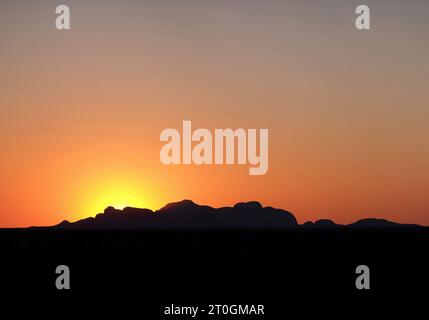 Kata Tjuta, (die Olgas) eine orange Silhouette bei Sonnenuntergang. Ein dunkler Vordergrund, abgerundete Formen im Kata Tjuta Nationalpark, ein verlaufender Himmel im Northern Territory Stockfoto