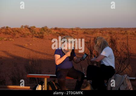 Getränke und Häppchen vor dem Abendessen auf einer Bank zwischen Dünen an der Aussichtsplattform Uluru & Kata Tjuta bei Sonnenuntergang, Sounds of Silence Outback Dinner Experience Stockfoto