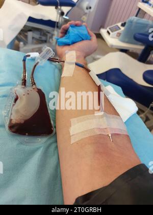 Arm des jungen Blutspenders während der Bluttransfusion zur Entnahme von Blutplasma und Blutplättchen Stockfoto