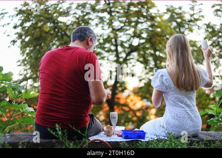 Ein Paar sitzt mit Weingläsern und hat Spaß, sich bei Sonnenuntergang im Hinterhof zu unterhalten. Verbringen Sie Sommerzeit und feiern Sie eine Party im Freien Stockfoto