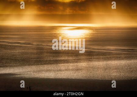 „Devon Gold“: Farbenfrohes, goldenes Licht bei Sonnenuntergang, Bild mit Blick über Saunton Sands und das Meer in Bideford Bay im Winter. Stockfoto