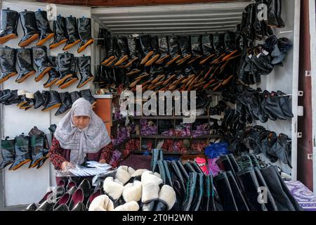 OSH, Kirgisistan - 6. Oktober 2023: Eine Frau, die Schuhe auf dem Jayma Basar in Osh, Kirgisistan verkauft. Stockfoto